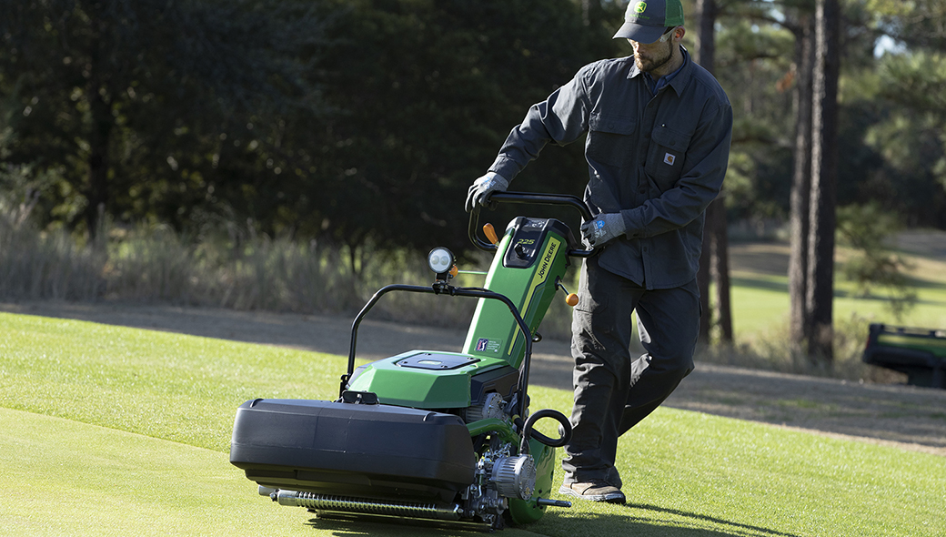 Action shot of a man operating a 225 E-Cut Electric Walk Greens mower on a golf course