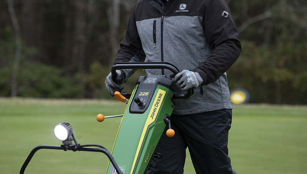 Close-up view of a person operating a 225 E-Cut Electric Walk Greens mower on a golf course
